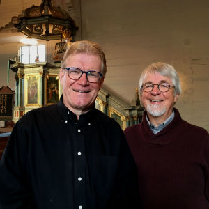 Lars-Johan Sandvik är predikant i kyndelsmässodagens gudstjänst och Johan Klingenberg är liturg. Lars-Johan Sandvik och Johan Klingenberg ser glada in i kameran, i bakgrunden predikstolen i Nykarleby kyrka.