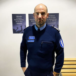Patrik Karlsson iklädd polisens kontorsuniform tittar in i kameran med händerna i fickorna.