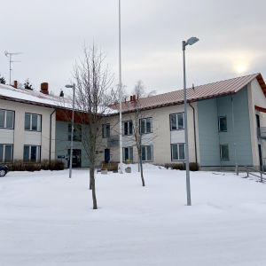 En byggnad i två våningar som fungerar som ett äldreboende. På marken ligger snö.