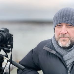 En man i vinterkläder står intill sin uppriggade kamera