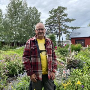 Krister Stenback står framför en blommande trädgård.