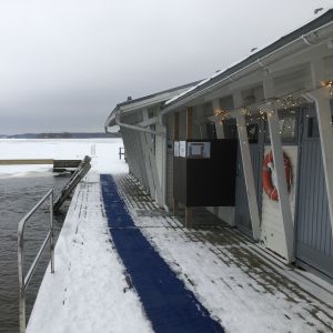 Vinterbadplats i Ekenäs med snö och matta på bryggan till platsen där man doppar sig.