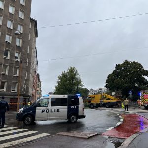 Helsingin Ruoholahdessa poliisi ja pelastuslaitos korjaavat raitiotien pudonneita johtimia. Kuvassa hälytysajoneuvoja ja tie suljettuna.