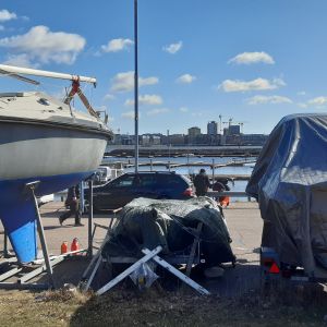 Får båten stå på land? Esbo tog beslutet att båtägare inte behöver sjösätta sin båt den här säsongen på grund av coronavirusepidemin. Upptagen segelbåt och andra båtar under presenning i småbåtshamn i Helsingfors.