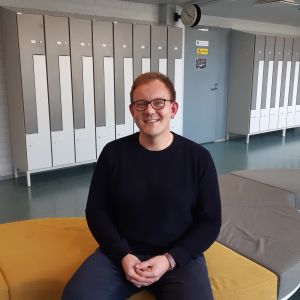Positivt att studentexamen används mer i antagningen till högskolor. Det lägger mer vikt på det man gör i gymnasiet anser studiehandledare Tony Valtonen. Tony Valtonen studiehandledare i Mattlidens gymnasium sitter i skolkorridoren på en gul soffa och i bakgrunden elevernas skåp.