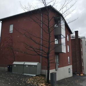 Punainen pienkerrostaloa Tampereen Armonkalliolla. Talon takana näkyy vanhempi punatiilinen kerrostalo ja Näsijärveä.