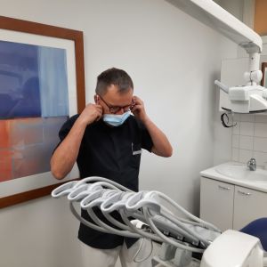 Ansvariga tandläkaren Kaj Karlsson klär på sig sitt munskydd.