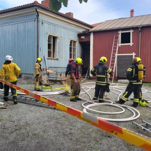 Brandmän som står på en innergård. 