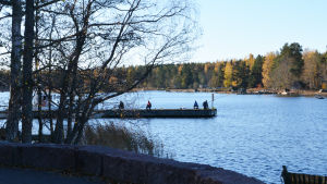 Här kan det i framtiden finnas en hel semesterby, om Lehtis planer kommer till skott. Arkivbild från 2018. Silhuetterna av fiskare på en brygga med havet i bakgrunden.