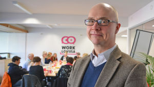 Mats Åminne deltog i workshoppen. Han jobbar som försäljnings- och marknadsföringsdirektör. Närbild på en medelålders man i kavaj. Han ser in i kameran och ler lite. Bakom mannen synns ett bord kring vilket det sitter flera personer och jobbar.