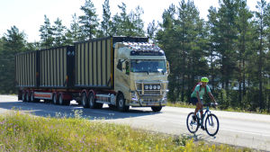 På riksväg 25 delar du väg med väldigt stora, tunga fordon. En cyklist cyklar på en riksväg. Bakom cyklisten kör en stor långtradare.