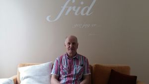 Leif Olin i soffan framför ett bibelcitat på väggen i Sundom Missionskyrka.