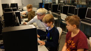 Robotinitiativtagaren Tiina Korhonen, som är på tillfälligt besök i skolan, hjälper några elever i datasalen. robotprogrammering