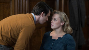 Den unga Joan spelas av Glenn Close egen dotter Annie Stark. Närbild på Joan (Annie Starke) då hon sitter på en stol och Joe (Harry Lloyd) böjer sig över henne för att förklara vad han menar.
