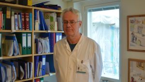 Chefsläkare Peter Braskén befarar att vården i Västnyland slås i spillror. Man som står framför en bokhylla och ett fönster.