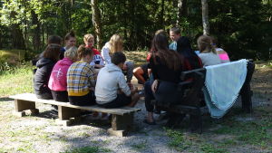 Efter varje programpunkt diskuterar gruppen tillsammans om hurdana tankar som väcktes. Lägerdeltagare och ledare på Prometheus-lägret i Lojo sitter på bänkar på en gård och diskuterar.