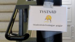 Det är gymnasiets tvåor som får fungera som provkaniner under testet. Skylt med texten "Tystnad, studentskrivningar pågår".