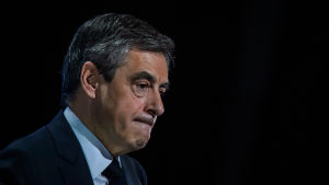 François Fillon François Fillon tittar ner i golvet, står mot en mörk bakgrund.