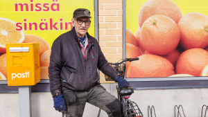 Pyttisbon Karl Boman tror flygplatsen är en bra sak. En äldre man håller i en cykel. Han står utanför en mataffär.
