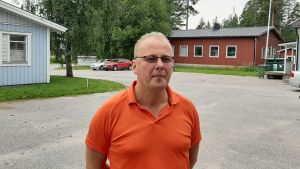 Kunder funderar varför grannen har jordvärme, men vi får inte skaffa jordvärme, berättar vd Peter Söderlund på Max´s. Man med orange skjorta och glasögon. I bakgrunden bl.a. byggnader.