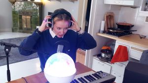 Ilon jobbar med idéfrön vid sitt köksbord, under discolampans ljus. Ilon vid synth på sitt köksbord, lägger på sig hörlurar, discolampa i förgrunden.