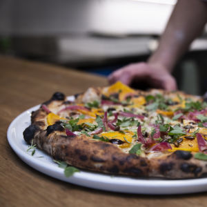 Pizzan gräddas snabbt i vedugn. Bottnen är enligt Victorzon pizzans viktigaste beståndsdel. Närbild på en färdiggräddad pizza på en tallrik.
