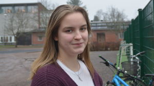Kaisla Dahlqvist är ordförande för Raseborgs ungdomsfullmäktige. En ung kvinna ute på skolgård. Karis svenska högstadium och Karis-Billnäs gymnasium i bakgrunden.