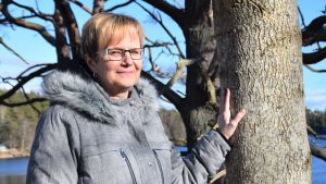 Linnéa Nystedt är nöjd över att få trädgårdsarbeta på stugan i stället för att sitta isolerad i sin lägenhet. Linnéa Nystedt står vid ett träd och tittar in i kameran.