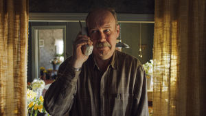 Nisse (Peik Stenberg) vill inte svara i telefon och lyssna på alla som beklagar sorgen. Nisse (Peik Stenberg) står med en telefonlur i handen och lyssnar.