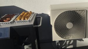 Luftvärmepumpar har ofta en låda inomhus och en annan utanför huset. I det här radhuset i Esbo har utenheten placerats invid grillplatsen på verandan. En luftvärmepump på en veranda i Esbo.