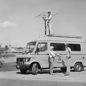Att åka ut och sända från ort och ställe har alltid varit viktigt för Radio Västnyland. Bilden är tagen 7.6.1984. På taket ljudtekniker Bo-Erik Ekholm med redaktörerna Lena Bergman och Uffe Wikström vid sändningsbilen. Två personer står vid en radiosändningsbil medan en tredje står på bilens tak.
