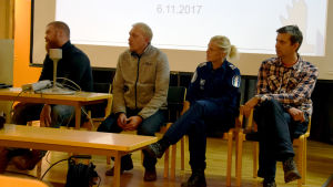 Antti Piironen och Visa Eronen från Finlands viltcentral, kommissarie Maria Sainio från Raseborgspolisen och Antti Härkälä från Naturresursinstitutet svarade på frågor. Antti Piironen, Visa Eronen, Maria Sainio och Antti Herkälä sitter på stolar på en mindre scen.
