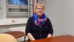 Enligt rektor Riitta Liias-Lepistö fungerar språkbad så att det blir mindre språkbad i de högre klasserna. Portättfoto av en kvinna som sitter vid ett bord och ser in i kameran.