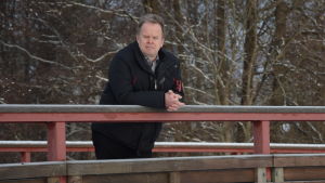 Jarl Boström var tidigare kommundirektör i Ingå. Ingås kommundirektör Jarl Boström lutar mot ett broräcke.