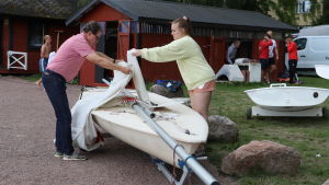 När seglatsen är över är det viktigt att komma ihåg att vika ner seglet på rätt sätt. Två personer viker ner seglet på en Zoomjolle.