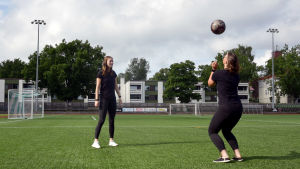 Fotbollsspelarna Felicia Gröning och Jill Illman fungerar som förebilder för de yngre tjejerna i klubben då de spelar i damlaget. Två unga kvinnor står och sparkar en fotboll till varandra på en konstgräsplan.
