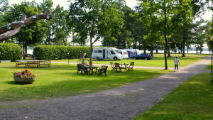 Familjen Parviainen tycker om campingområdet. Ett capingområde med några husbilar i bakgrunden och en sandväg som går ner till vattnet.