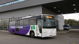 Studerandena har tidigare kunnat anlita Pohjolan Liikenne. En lila och vit buss som står på en busstation. I bakgrunden en stor grå byggnad.