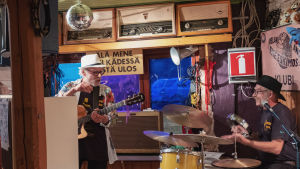 Aslak Christiansson ja naapuri Arto Tyrni vastaavat illan musiikillisesta annista. Aslak Christiansson ja Arto Tyrni soittamassa, juttelevat toisilleen baarin soittonurkkauksessa Aslak and the Eskimos -klubilla