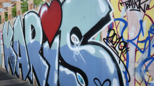 Hjärtat ska sprida glädje. Karis textat i graffiti i blått med hjärta som i-prick.