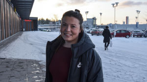 Sabina tänker på djuren. Ung kvinna står utomhus på parkering, ler och tittar in i kameran. Snö på marken.