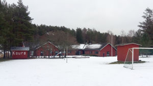 Koupo lägergård i vinterskrud. Hit flyttade Sunnaberg skola i januari 2019. Röda låga lägerskolbyggnader.