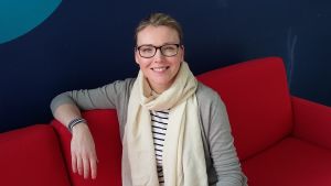 Katarina Paasi har lång erfarenhet av renoveringar. Katarina Paasi sitter på röd soffa.