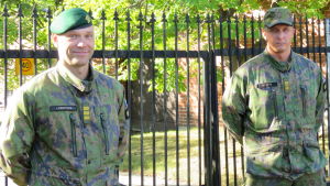 Beredskapschef Mikael Lindroos och röjningsofficer Henri Helste står på lämpligt avstånd från varandra. Det här på grund av rådande coronarekommendationer. Två officerare i militäruniform står vid Nylands brigads gamla järnport.