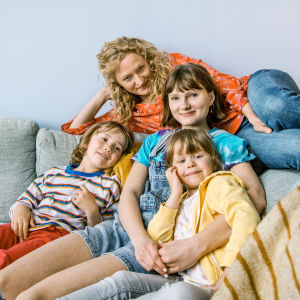 Ella tillsammans med sina tre barn, Noa, Siri & Hedvig. Karaktären Ella med sina tre barn i en soffa.
