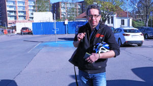 Jan Hellgren från Nationella centret för utbildningsvärdering. Jan Hellgren håller i en cykelhjälm på en parkeringsplats.
