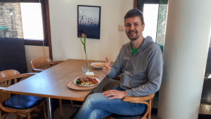 Antti Kuisma uppmanar alla att modigt ta sig ut och motionera. En man sitter vid ett bord och visar tummen upp.