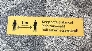 Klistermärken på golvet påminner resenärer på Helsingfors-Vanda flygplats att hålla säkerhetsavstånd. Pidä turvaväli!- tarra lentoaseman lattiassa.