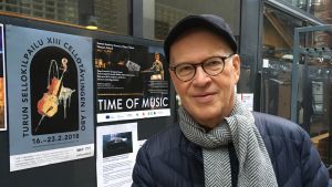 Timo Hanhinen brevid cellotävlingens plansch, vars bild han också målat. Timo Hanhinen