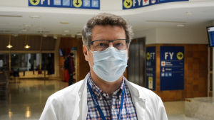 Juha Salonen, infektionsöverläkare på Vasa centralsjukhus, är försiktigt optimistisk inför den senaste statistiken över coronasmittspridningen i Österbotten. Men samtidigt är han rädd för att det inte ska komma tillräckligt med vaccin till Finland. Medelålders man i munskydd och läkarrock. I bakgrunden en sjukhusaula.